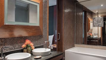 A modern bathroom with two sinks, a large mirror, and a bathtub.