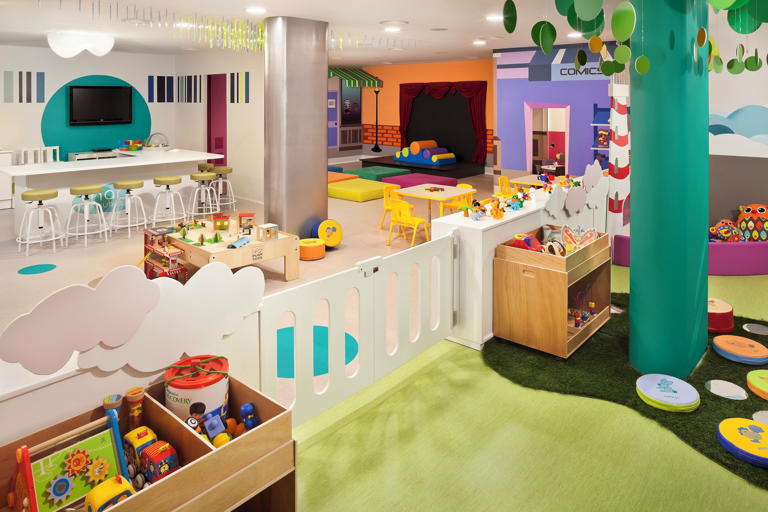 A children's play area with a TV, play tables, and a stage.
