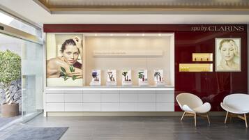 A spa by Clarins with a modern interior, a reception desk, and two white chairs.