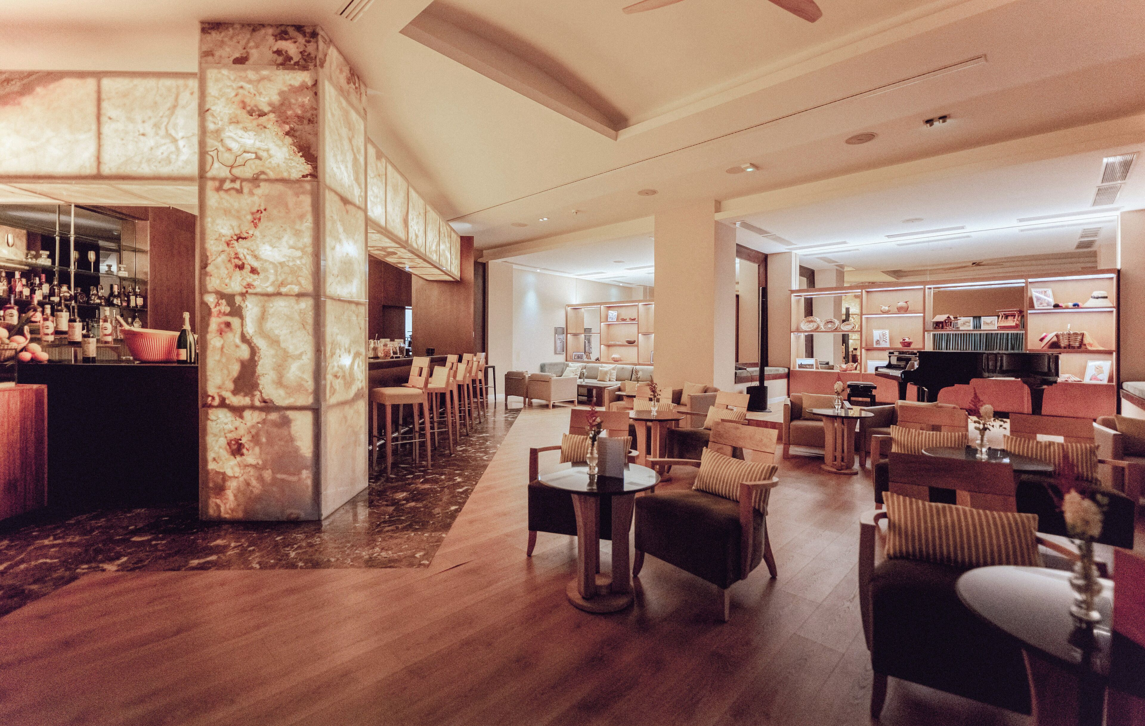 A hotel lobby with a bar area, seating arrangements, and a reception desk.