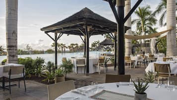 A resort patio with tables set for dining, overlooking a pool area with lounge chairs and umbrellas.