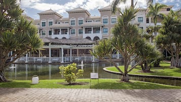 A hotel with a courtyard featuring a fountain, palm trees, and a brick pathway.