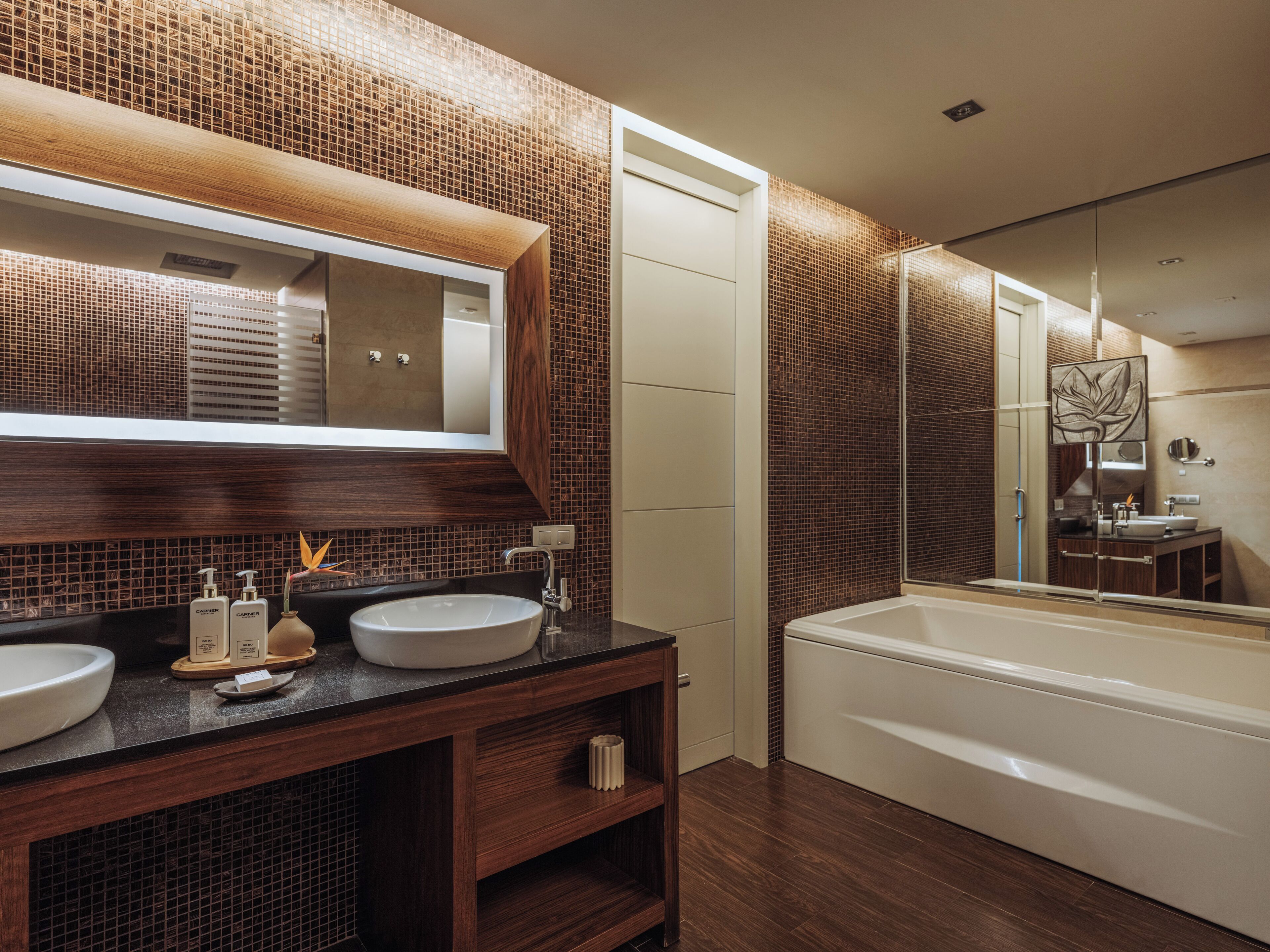 Un baño moderno con dos lavamanos, un espejo grande y una bañera.