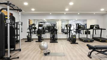Un gimnasio con diverso equipo de ejercicio, que incluye una estructura para sentadillas, cintas de correr y una máquina de remo.