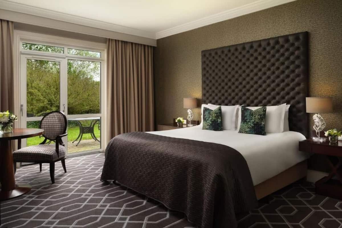 Ein Hotelzimmer mit einem großen Bett, Blick ins Freie, einem Essbereich und einem Vorhangfenster.