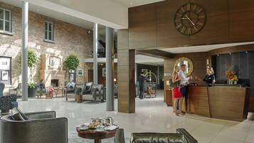 A spacious lobby with a reception desk, seating area, and a large clock.