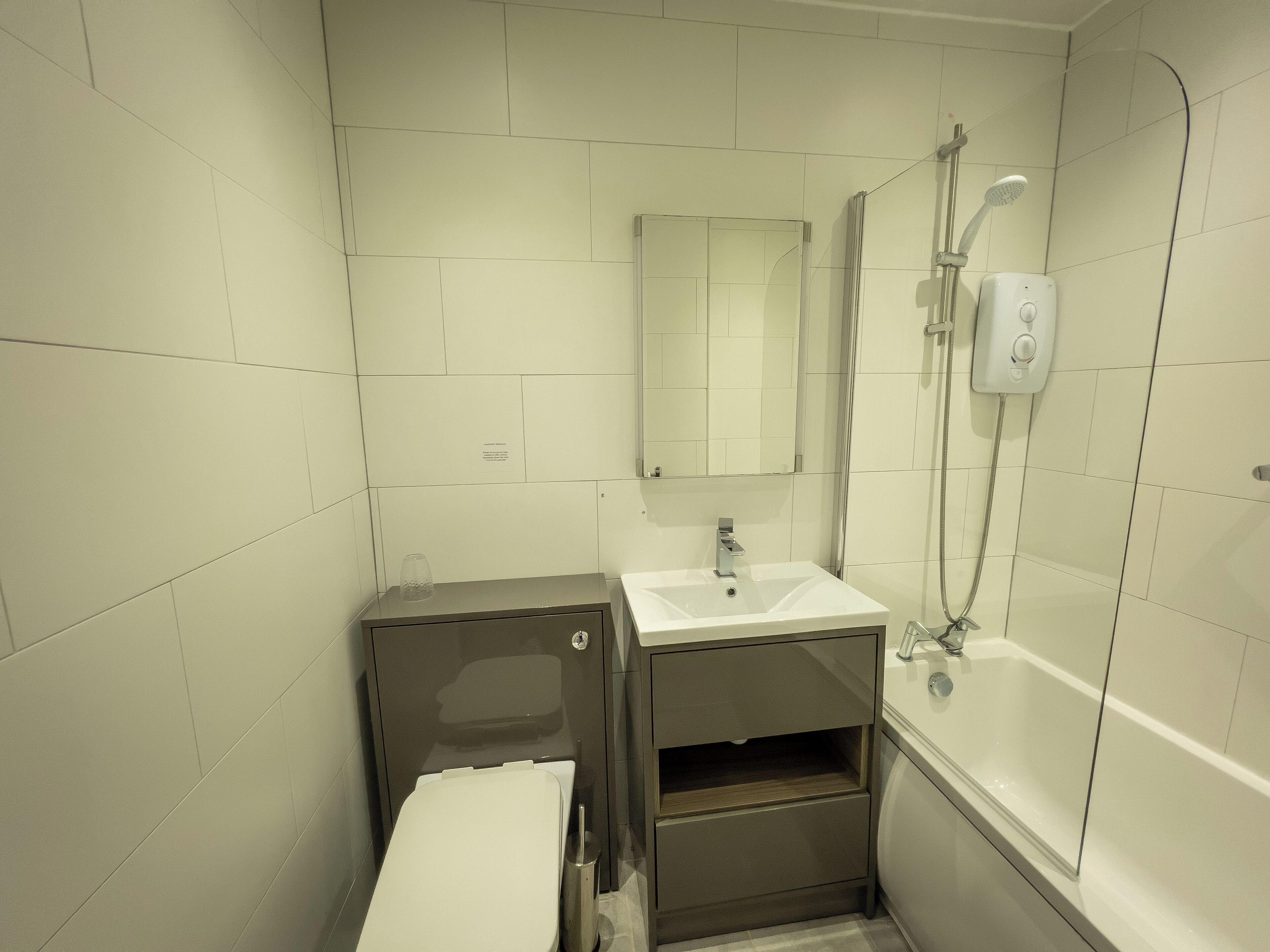 A modern bathroom with a toilet, sink, mirror, and shower.