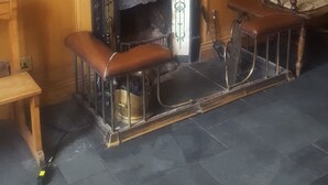 Ett mysigt rum med en öppen spis, en träbänk, en stol och en bokhylla.
