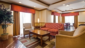 Un hall de hotel con un sofá, sillones, una mesa y una lámpara.