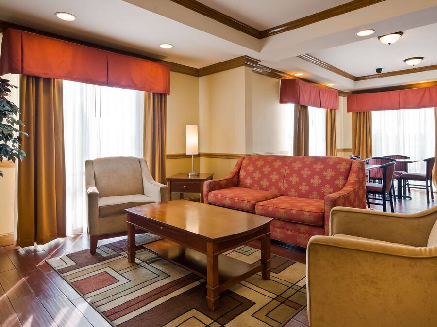 A hotel lobby with a sofa, armchairs, a table, and a lamp.