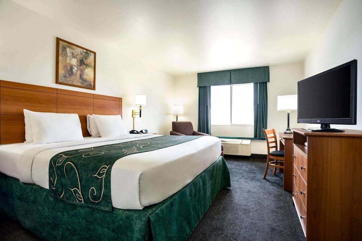 Ein Hotelzimmer mit Bett, Schreibtisch, Stuhl, Fernseher und Bildern an der Wand.
