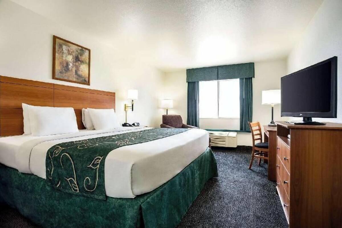 Ein Hotelzimmer mit Bett, Schreibtisch, Fernseher und Stuhl.