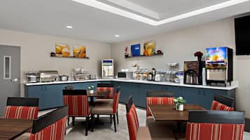 Una cocina moderna con una isla central, comedor con sillas tapizadas en rojo y un dispensador de zumo.