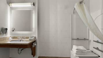Une salle de bain équipée d’un lavabo, d’un miroir, d’un porte-serviettes et d’un rideau de douche.
