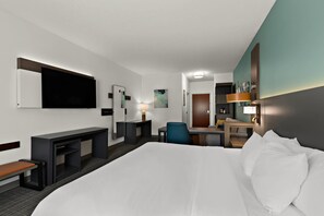 A hotel room with a large bed, a desk, a chair, a TV, and a small table with a lamp. - Comfort Inn Powell - Knoxville North (Powell)