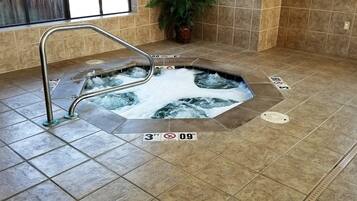 Relax in a hot tub surrounded by a large window and a potted plant.
