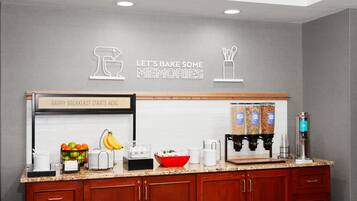 Una cocina con barra desayunadora, un cartel que dice 'Happy Breakfast Starts Here', y diversos electrodomésticos y utensilios de cocina.