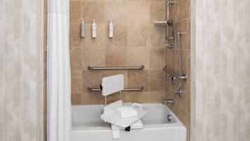 A bathroom with a bathtub, a shower, and a toilet. There are toiletries on the wall and a towel on the floor.