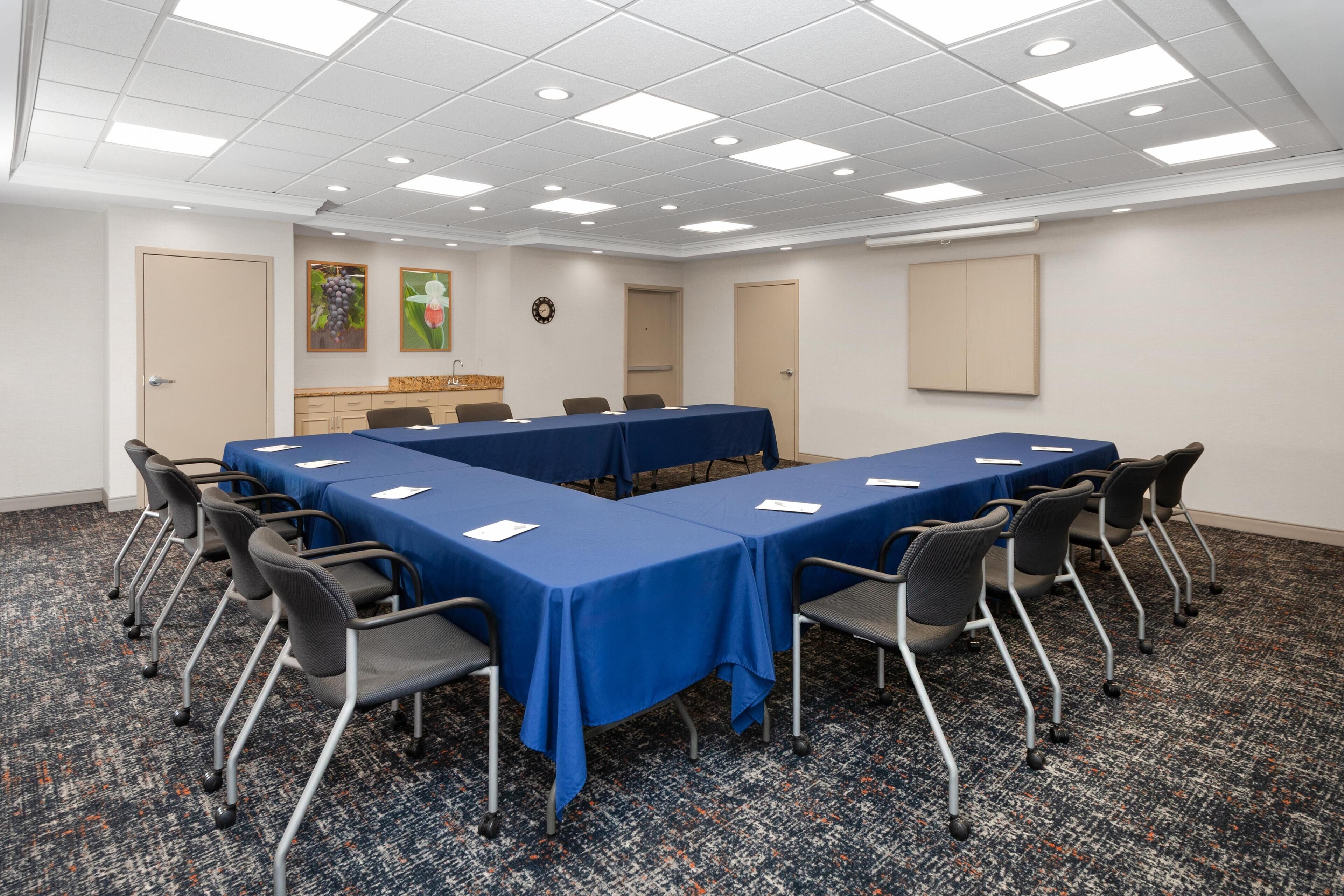 A conference room with a long table, chairs, and a carpeted floor.