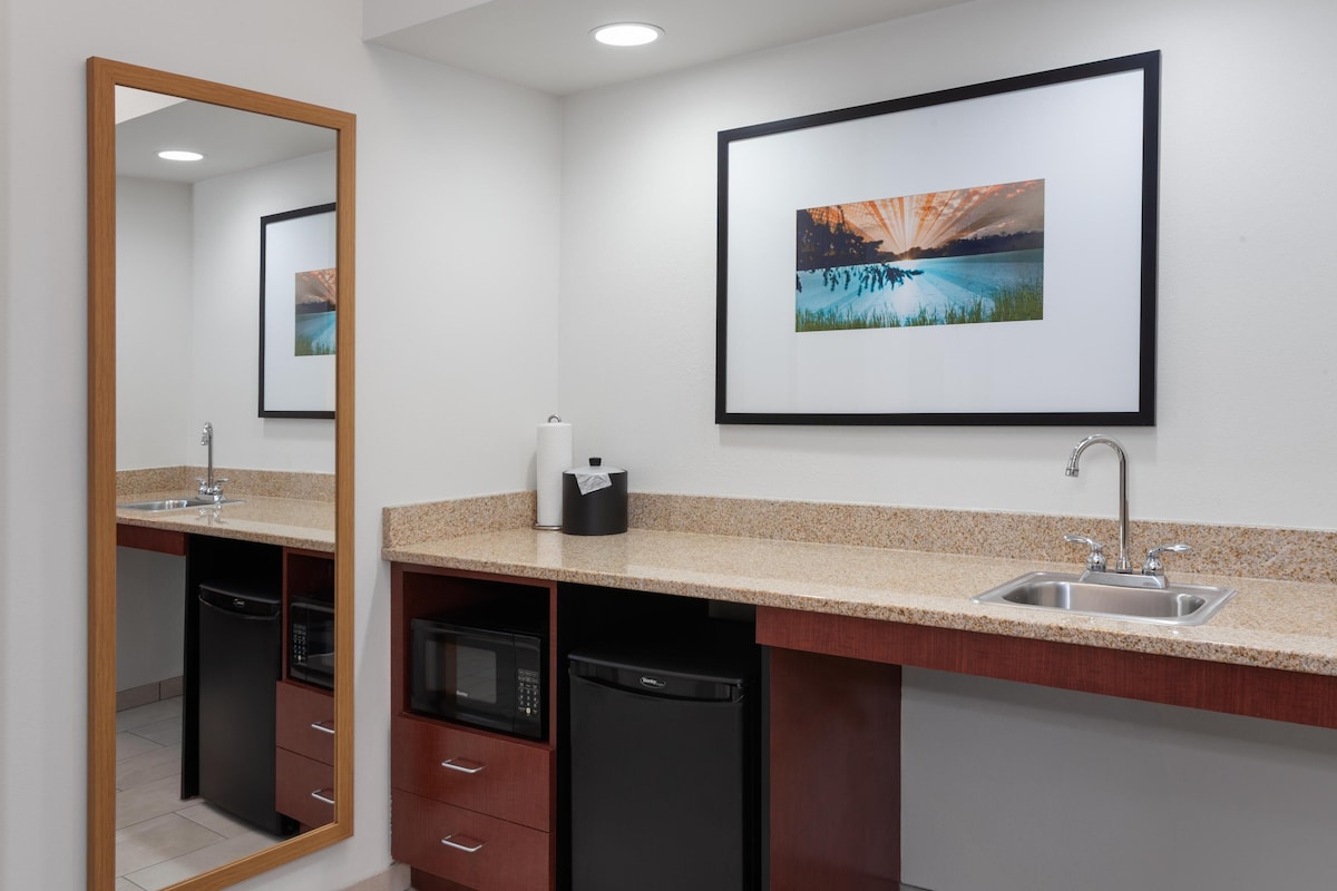 A bathroom with a sink, mirror, and a framed picture on the wall.