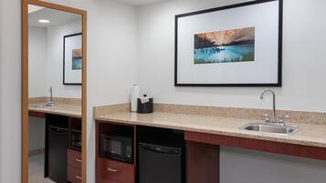 A bathroom with a sink, mirror, and a framed picture on the wall.