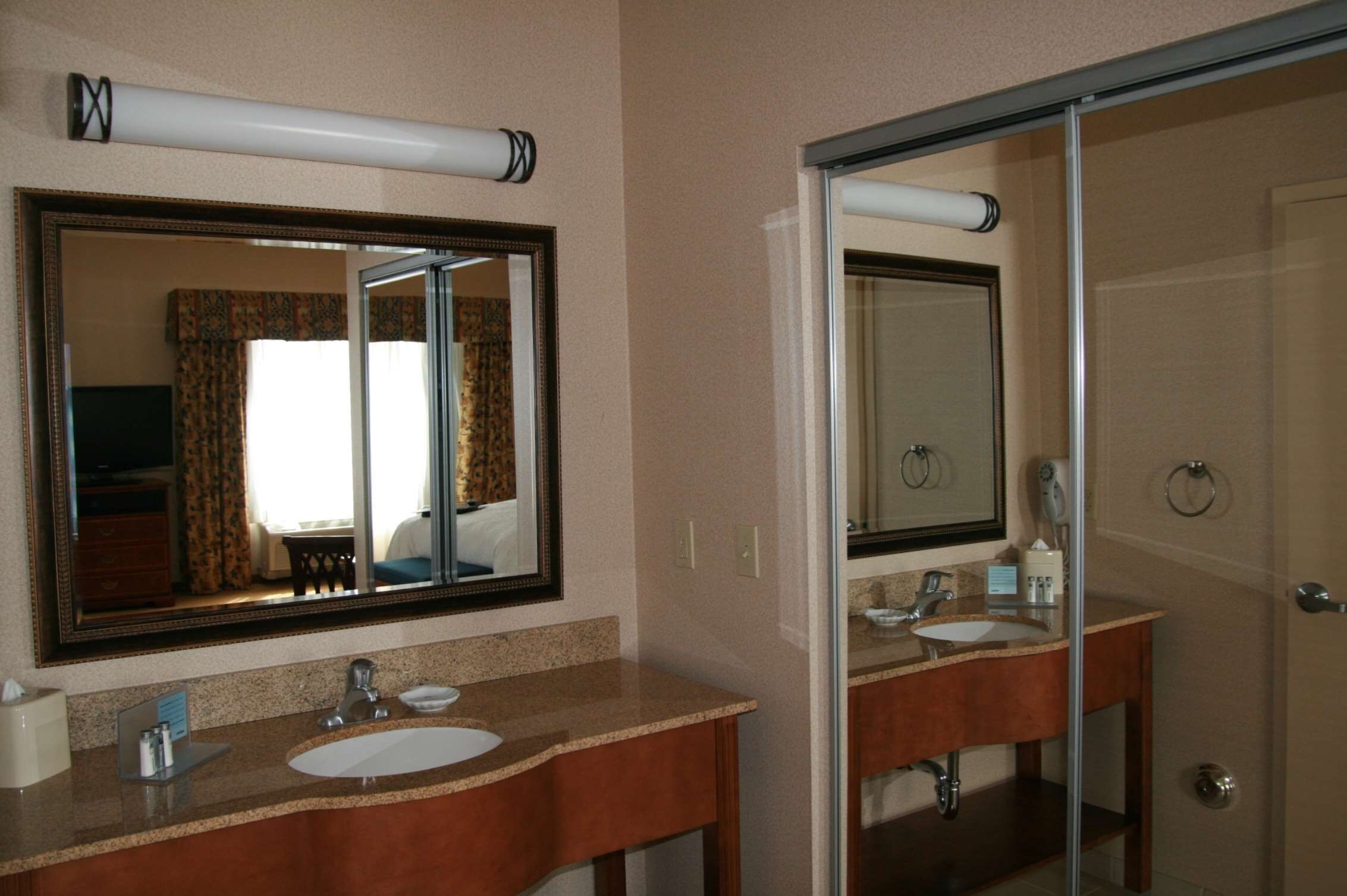 Un baño de hotel con dos lavamanos, un espejo grande y una zona de ducha.