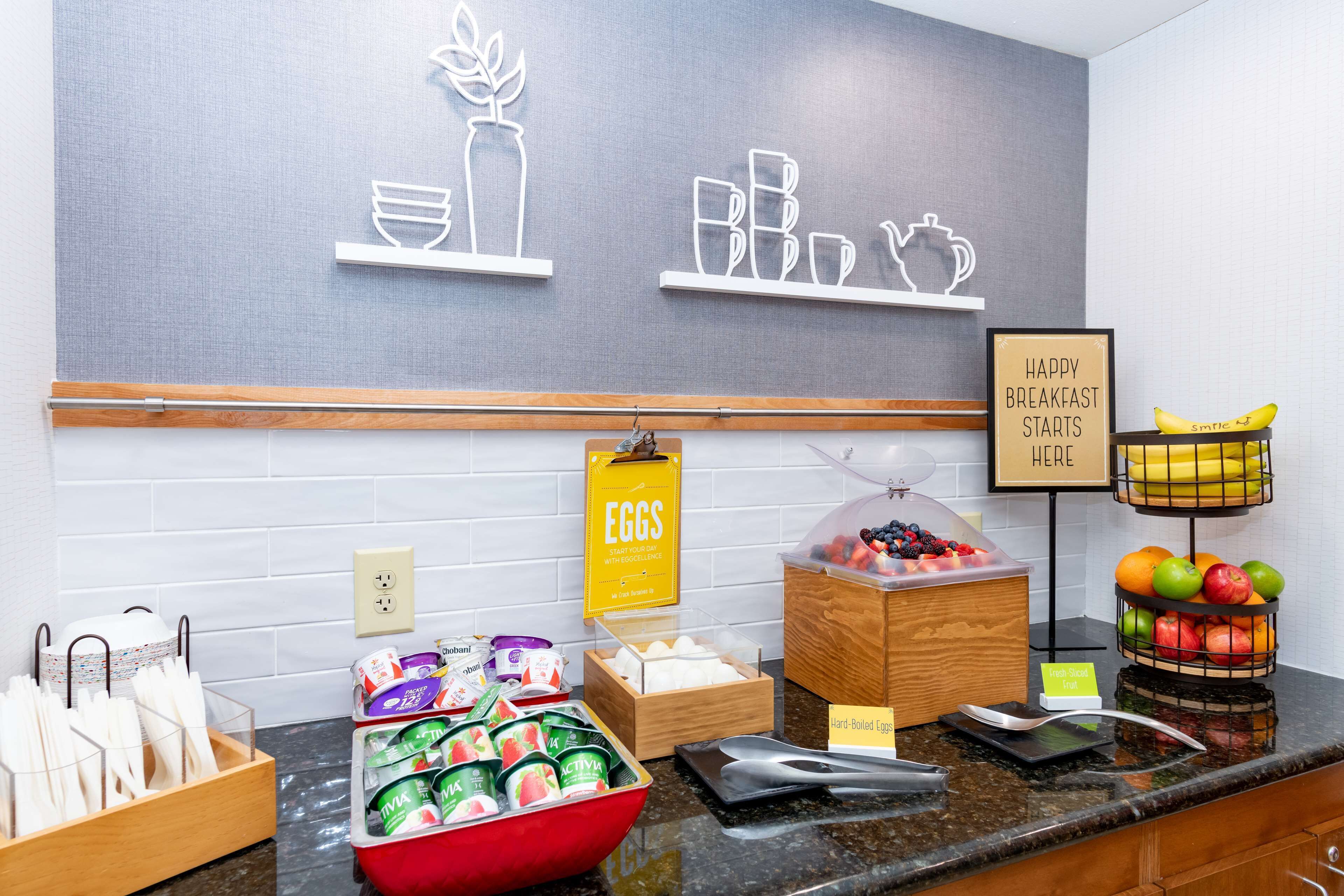 Zona de bufé para el desayuno con diversos alimentos y utensilios.