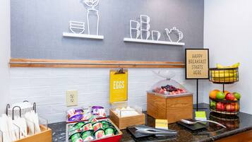 Zona de bufé para el desayuno con diversos alimentos y utensilios.