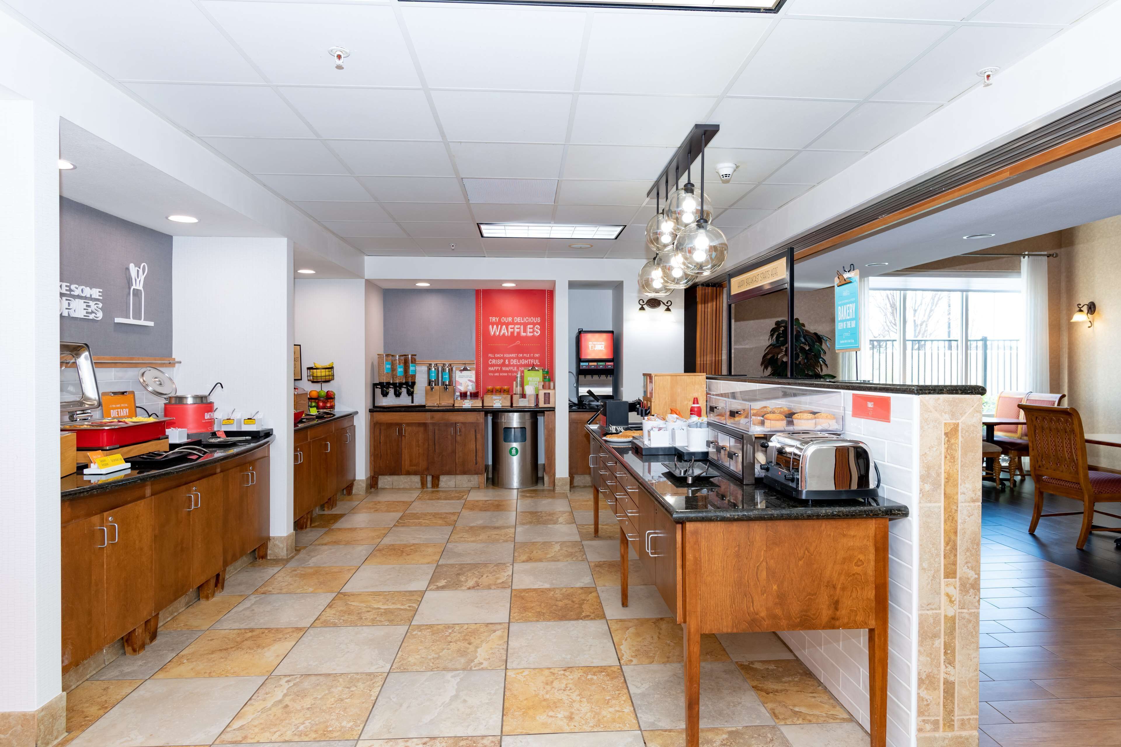 Una cocina de hotel con una zona de buffet, una estación de café y un cartel anunciando gofres.