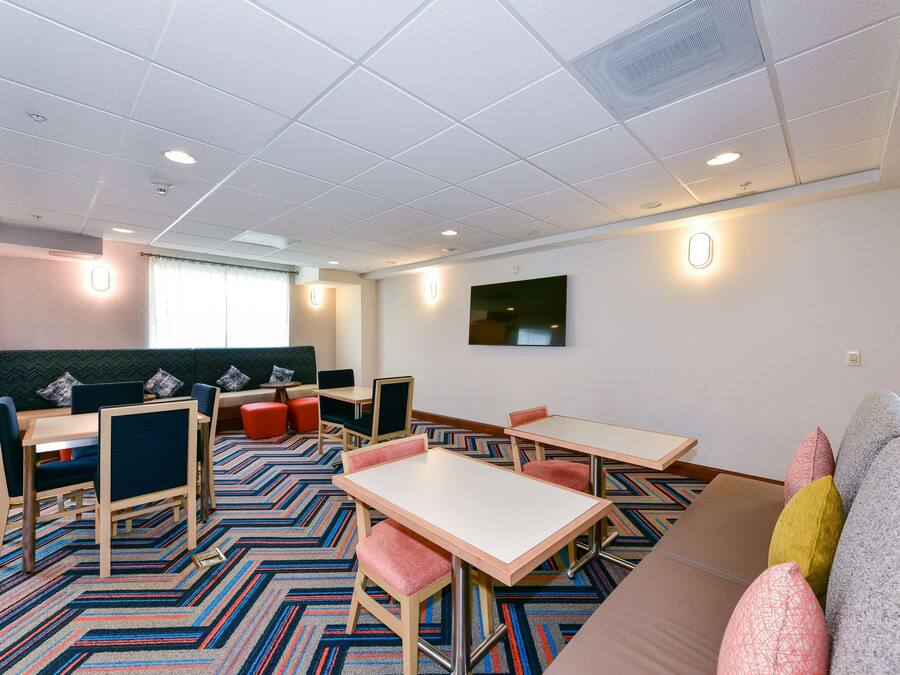 A hotel room with a large bed, a desk, a chair, a sofa, and a window with curtains.