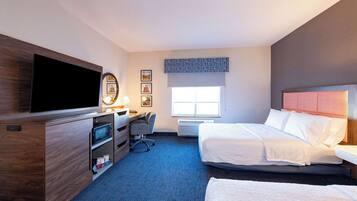 A hotel room with a flat-screen TV, a desk with a chair, two beds, a window with a view, and a ceiling-mounted light.