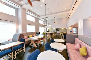 A modern dining area with tables and chairs, a sofa, and a ceiling fan.