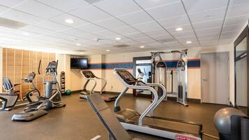 A gym with treadmills, elliptical machines, and a weight bench.