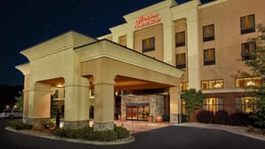 A hotel with a prominent entrance, a stone facade, and a clear night sky. - Hampton Inn & Suites Sevierville @ Stadium Drive (Kodak)