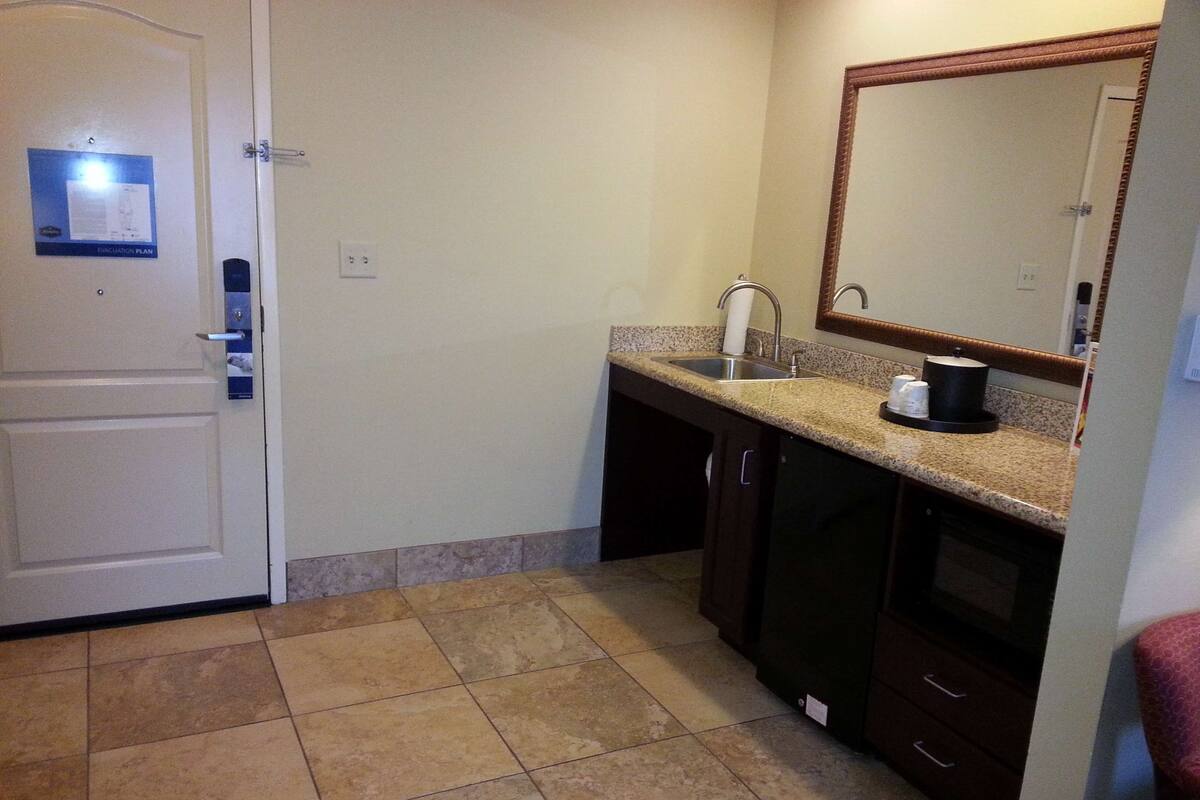 A compact kitchen with a sink, countertop, and a mirror above it.