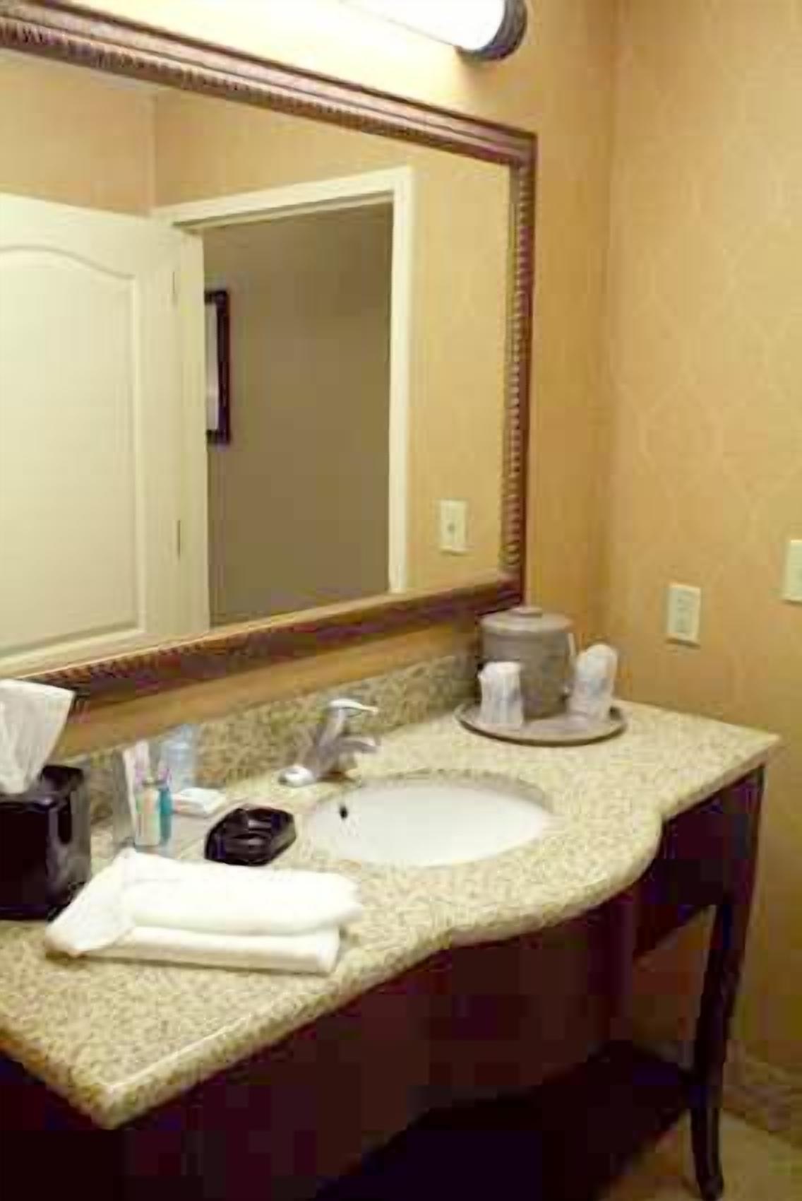 A bathroom with a sink, mirror, and toiletries.