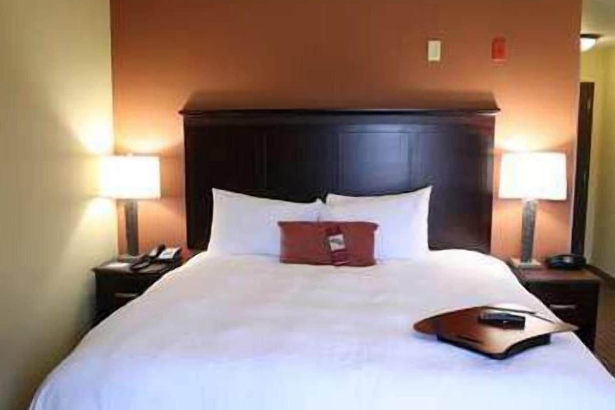 A hotel room with a large bed, two bedside tables, and two lamps.