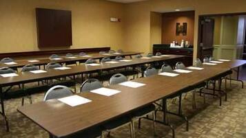 A conference room with long tables, chairs, and a podium.