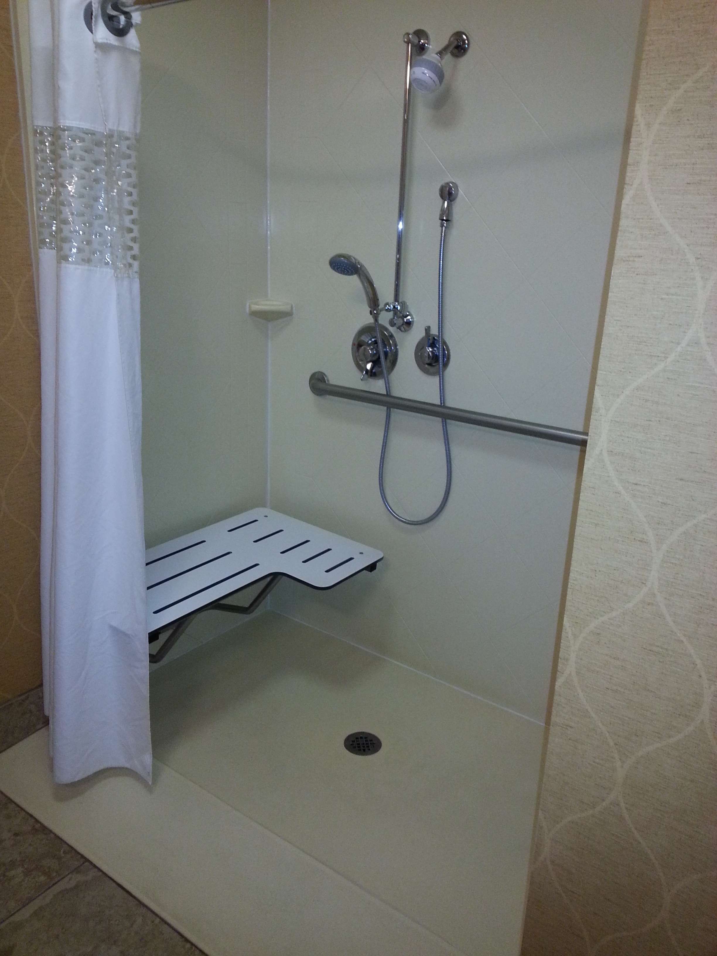 A small, enclosed shower area with a showerhead, handheld shower, and a towel rack.
