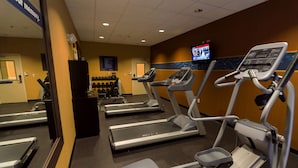 A gym with treadmills, a television, and a wall-mounted screen. - Hampton Inn & Suites Sevierville @ Stadium Drive (Kodak)