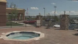 A fenced outdoor area with a hot tub, a building in the background, and a parking lot with cars. - Hampton Inn & Suites Sevierville @ Stadium Drive (Kodak)