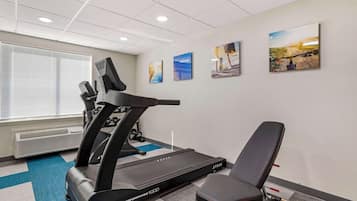 A gym with a treadmill, a stationary bike, and a bench. There are four framed pictures on the wall.