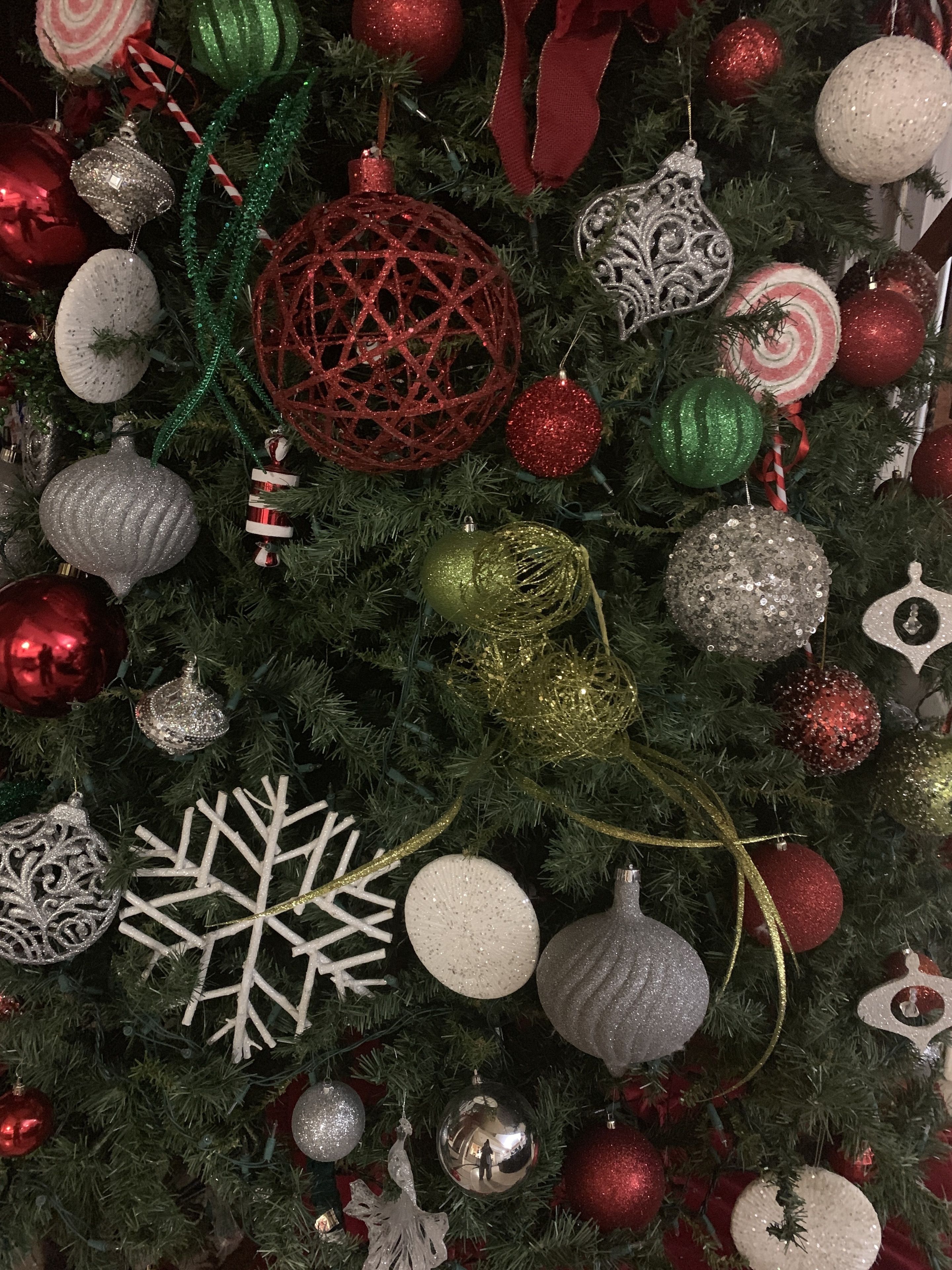 Un árbol de Navidad decorado con adornos variados, incluyendo esferas, un copo de nieve y bastones de caramelo.