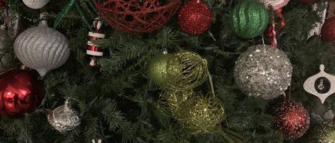 Un árbol de Navidad decorado con adornos variados, incluyendo esferas, un copo de nieve y bastones de caramelo.