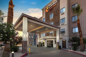 A Comfort Suites hotel with a modern facade, a covered entrance, and a landscaped area with palm trees and shrubs. - Comfort Suites Laredo - Nuevo Laredo (Laredo)