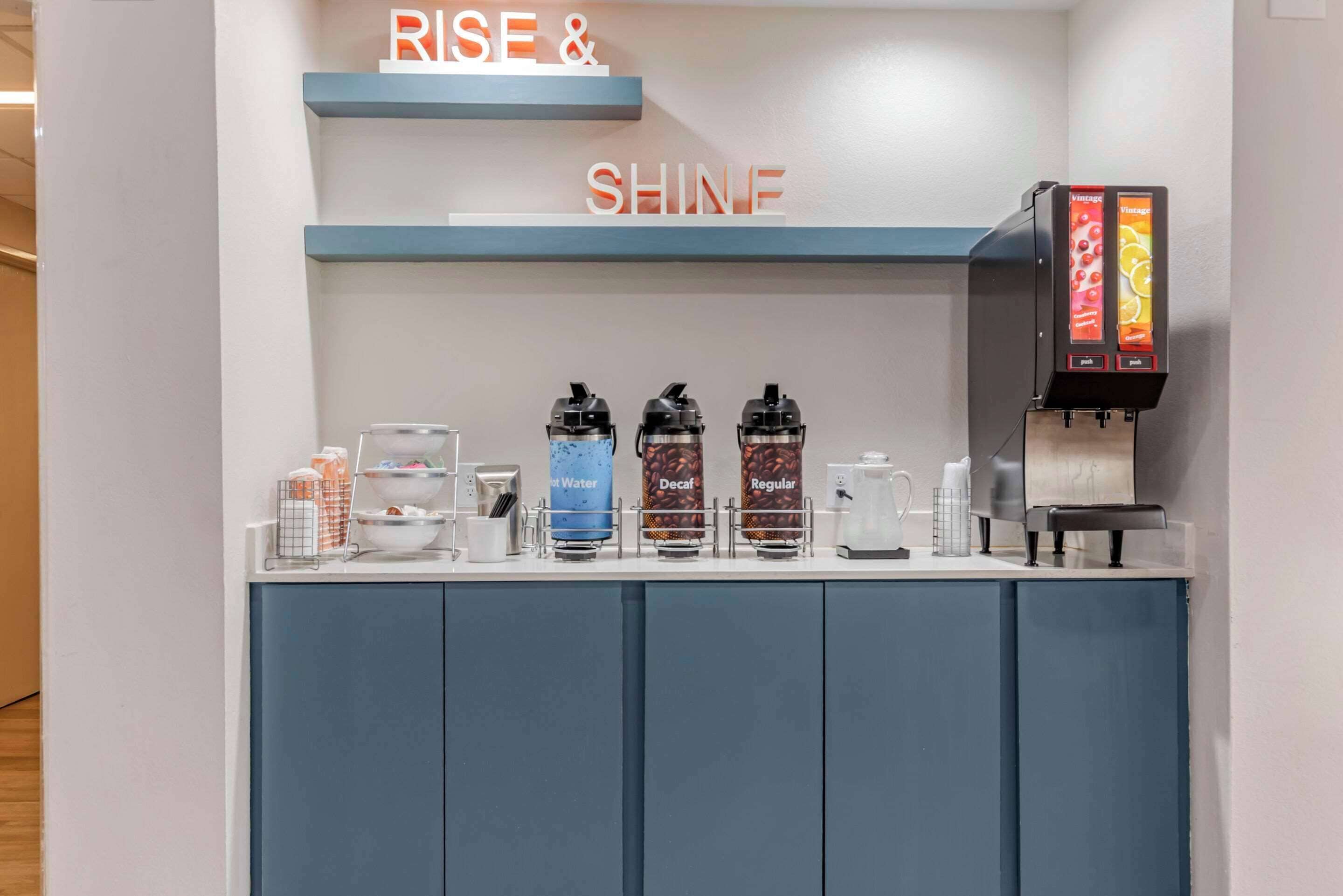 En kaffestation med tydligt märkta behållare för varmt vatten, koffeinfritt kaffe och vanligt kaffe, samt en kaffemaskin.