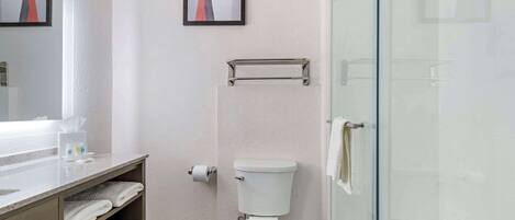 A modern bathroom with a toilet, a glass shower enclosure, a towel rack, and a sink with a mirror.