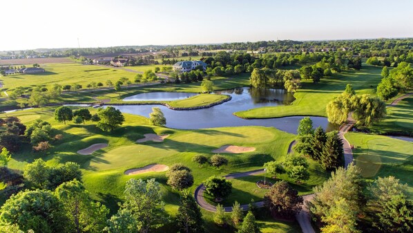 A golf course with water hazards, a clubhouse, and surrounding greenery. - Staybridge Suites Rockford by IHG (Rockford)