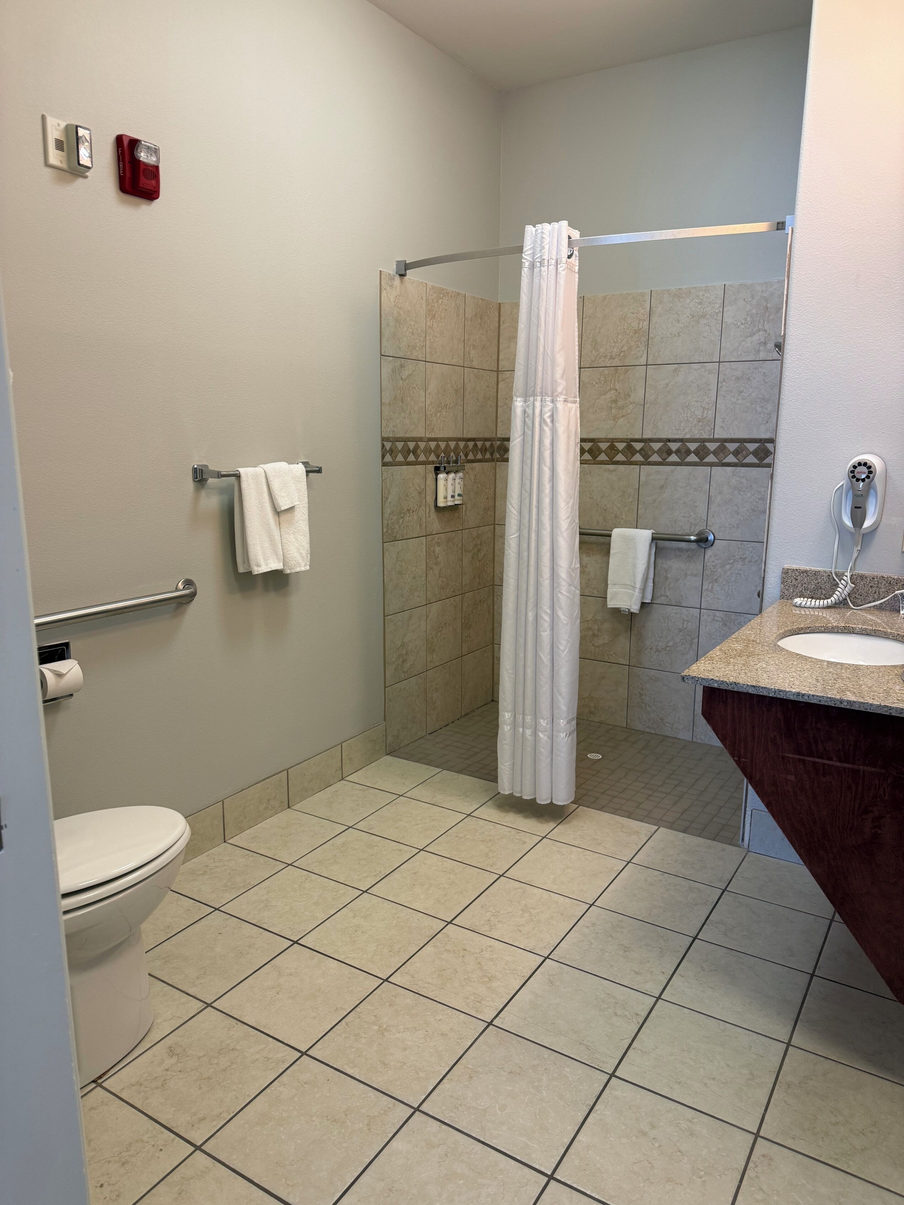 A bathroom with a toilet, shower, and sink.