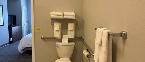 A bathroom with a toilet, towel rack, and a visible trash bin.